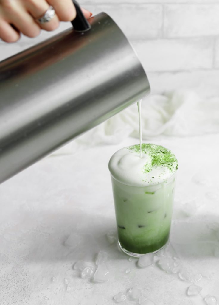 a vanilla iced matcha latte being poured 