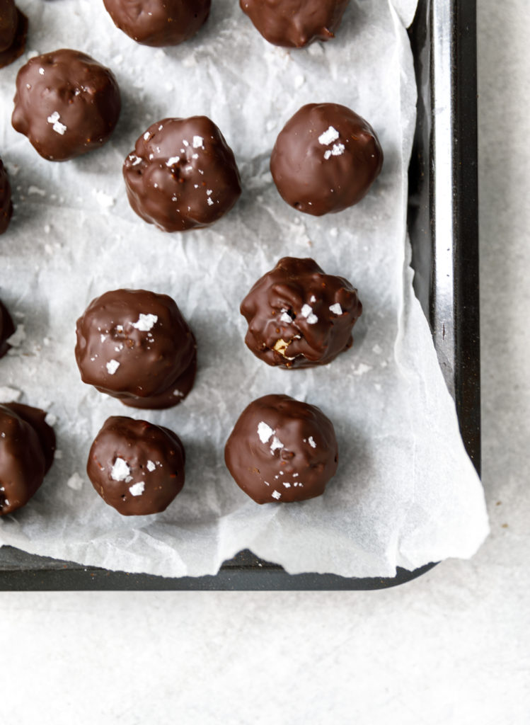 Chocolate fruit and nut balls on a baking tray lined with white parchment paper