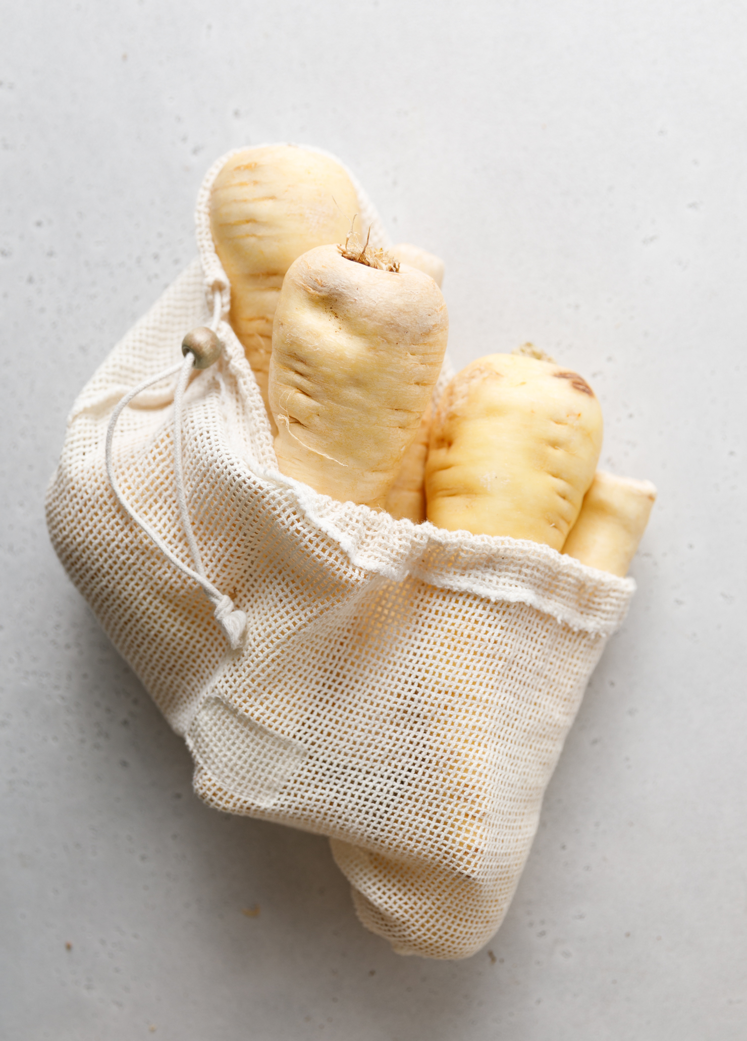 parsnips in a produce bag on a creamy grey backdrop