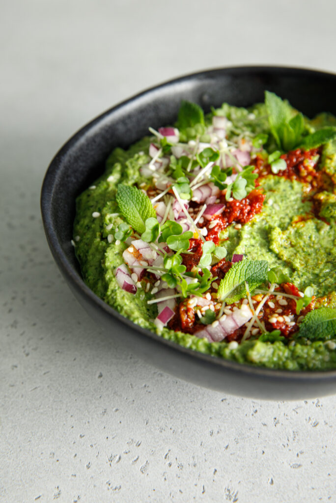 Black bowl of green pea, lentil and mint dip