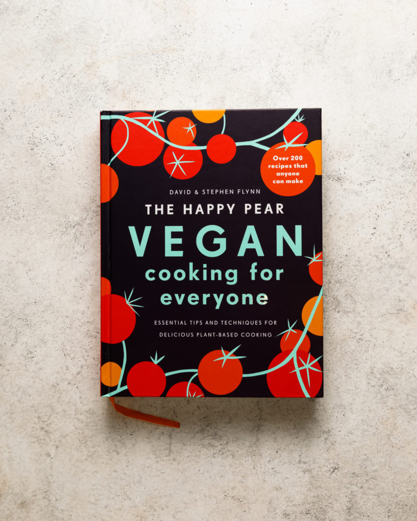 The Happy pear Vegan cooking for everyone cookbook on a beige textured backdrop