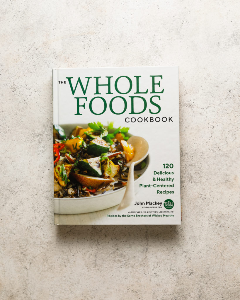 the Wholefoods cookbook on a beige textured backdrop