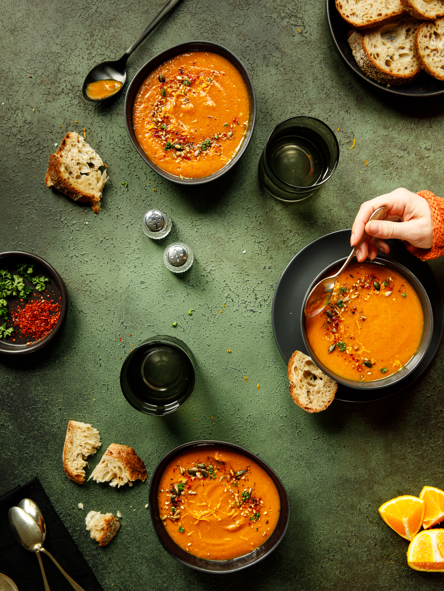 2 bowls Spiced sweet potato and orange soup on a green textured backdrop