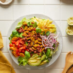 image of tropical cobb salad all plated up on a white ceramic plate on a white tiled backdrop