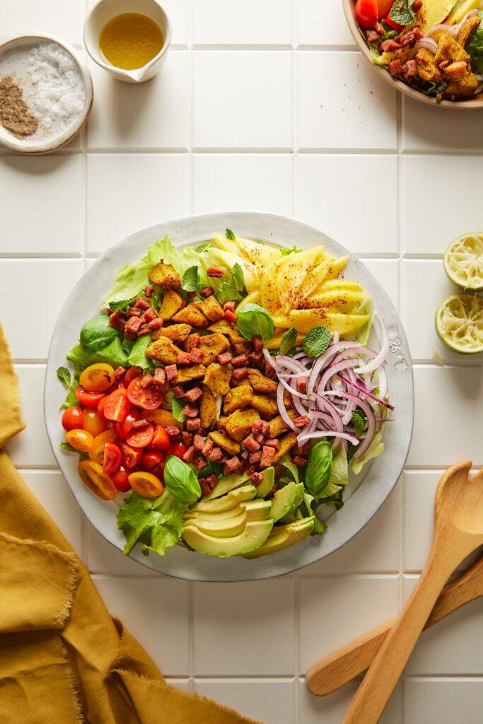 image of tropical cobb salad all plated up on a white ceramic plate on a white tiled backdrop