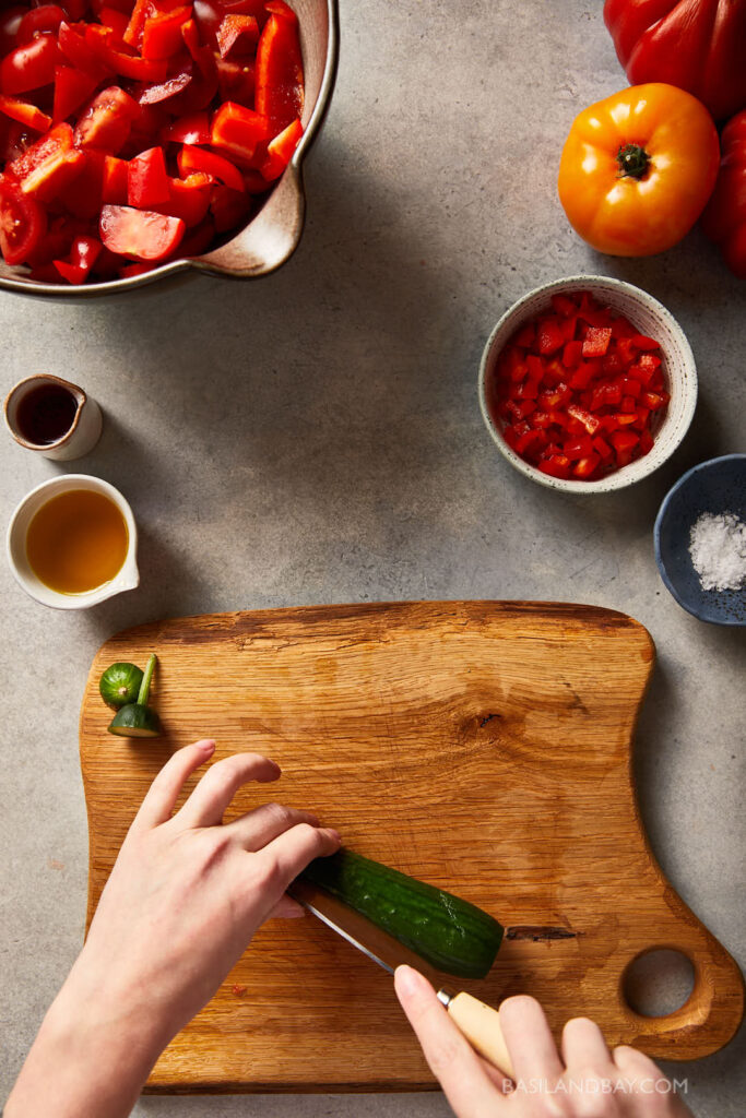 cucumber being diced into large chunks on a wooden chopping board