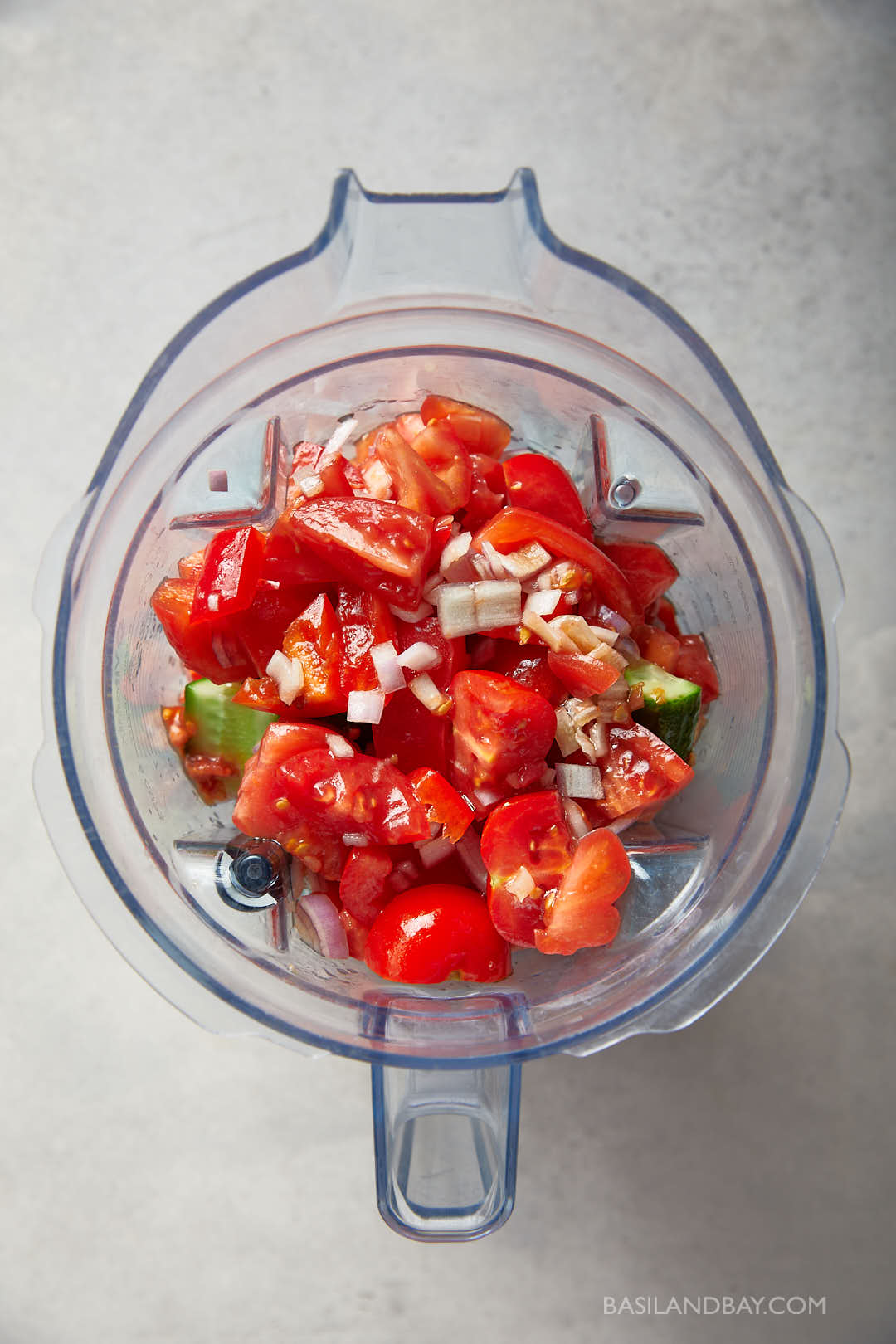 Chopped tomatoes, red pepper, cucumber, and shallot in a blender ready to blend