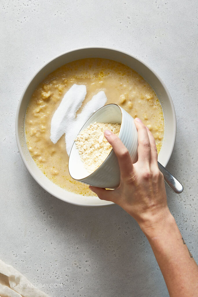 chickpea flour  being added to the wet ingredients in the large beige mixing bowl