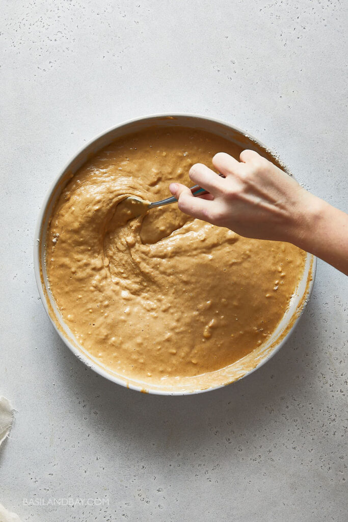 muffin batter being mixed in the  large beige mixing bowl