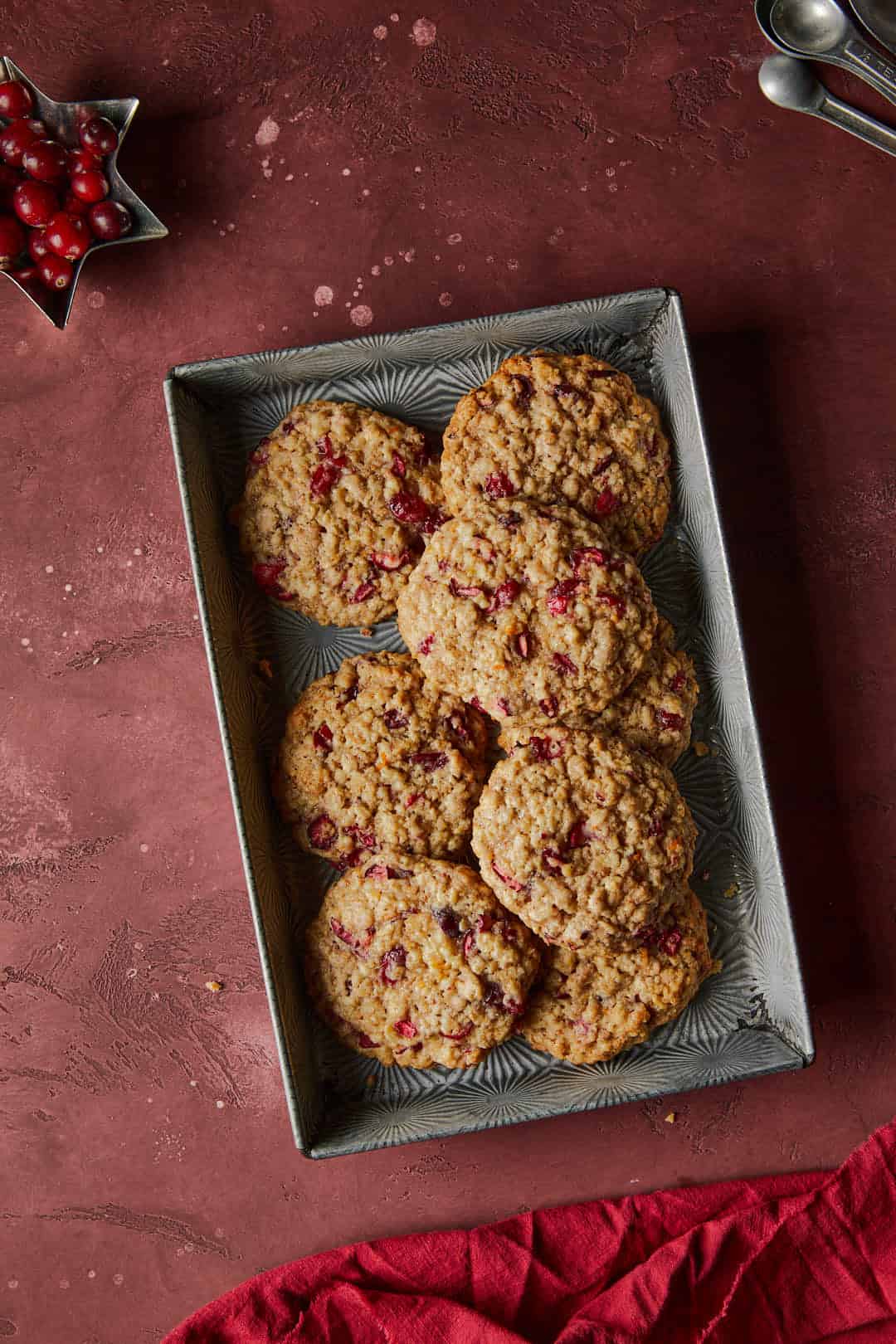 Cranberry Cardamom Oat cookies on a deep red backdrop with a red linen