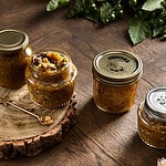 image of four green tomato chutney jars on a wooden backdrop