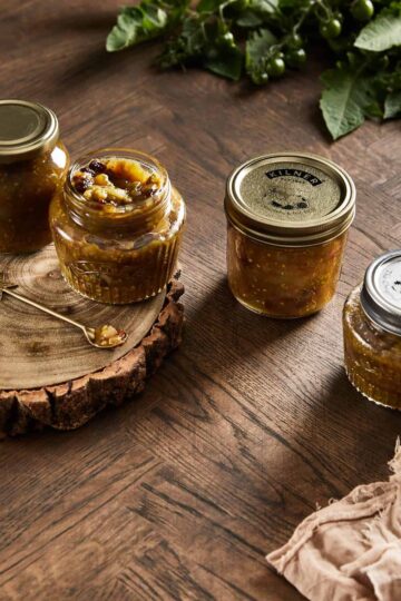 image of four green tomato chutney jars on a wooden backdrop
