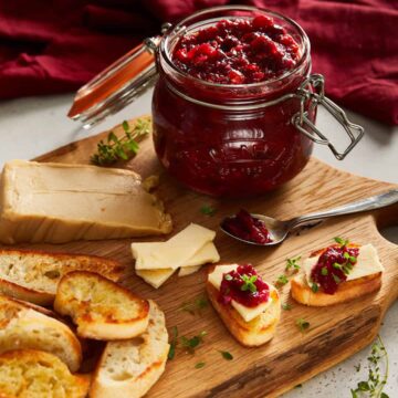 cranberry sweet chilli jam on a oak cutting board with little cheesy toasts