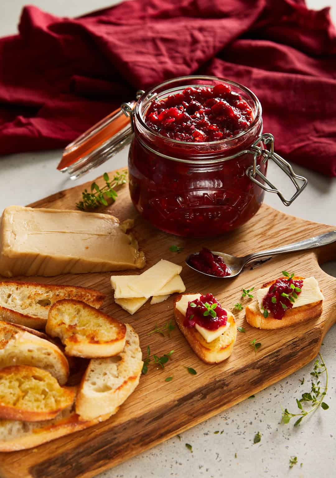 cranberry sweet chilli jam on a oak cutting board with little cheesy toasts