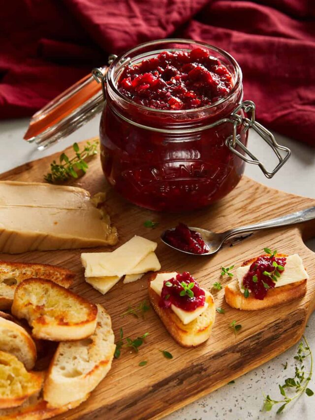 cranberry sweet chilli jam on a oak cutting board with little cheesy toasts