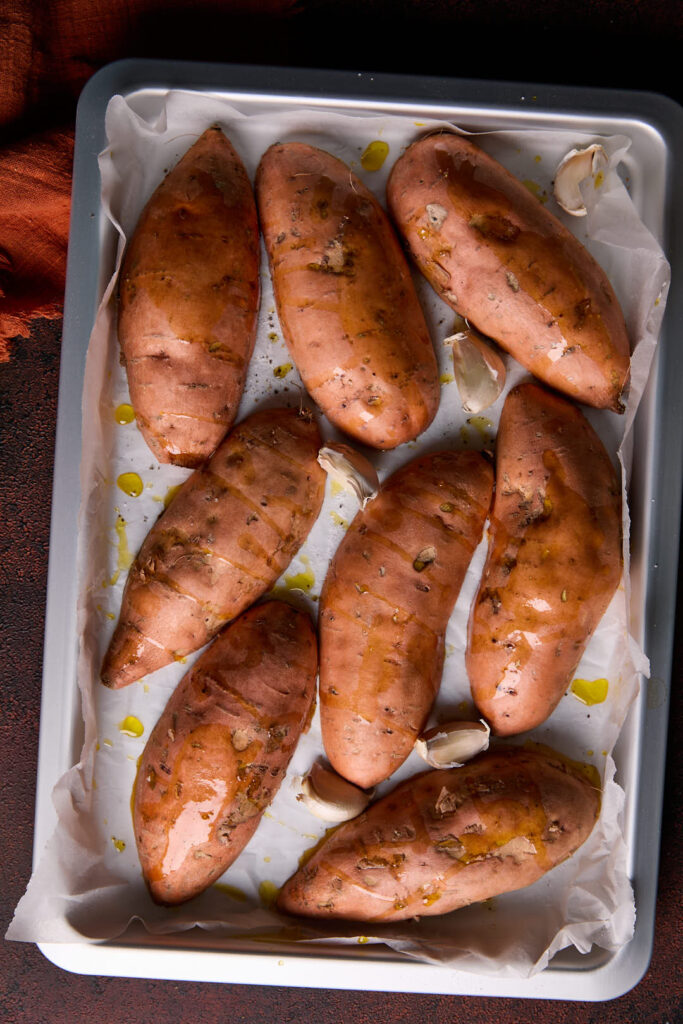 sweet potatoes  cut side down on a baking tray drizzled with olive oil and seasoned with salt and pepper