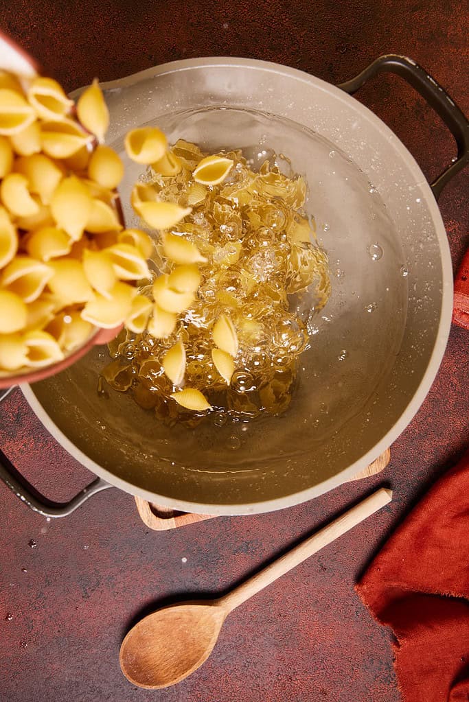 pasta shells being added to boiling water