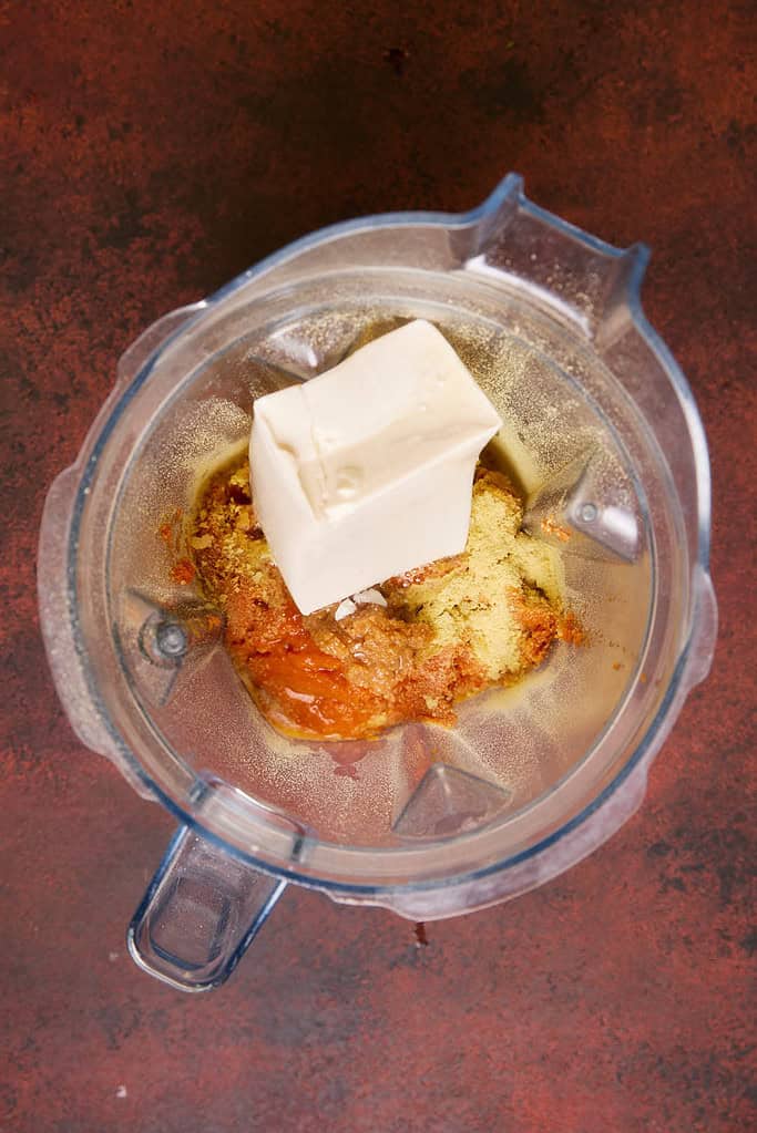 sauce ingredients in a blender jug with a block of silken tofu on top, ready to be blended 