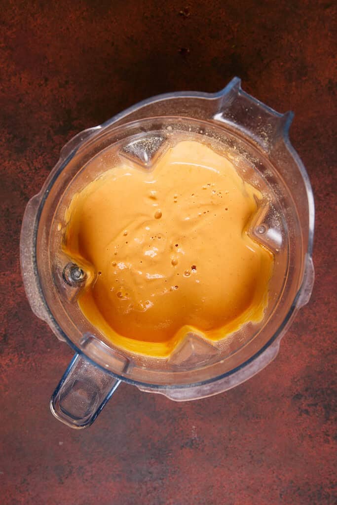 blended and smooth pumpkin mac and cheese sauce in a blender jug