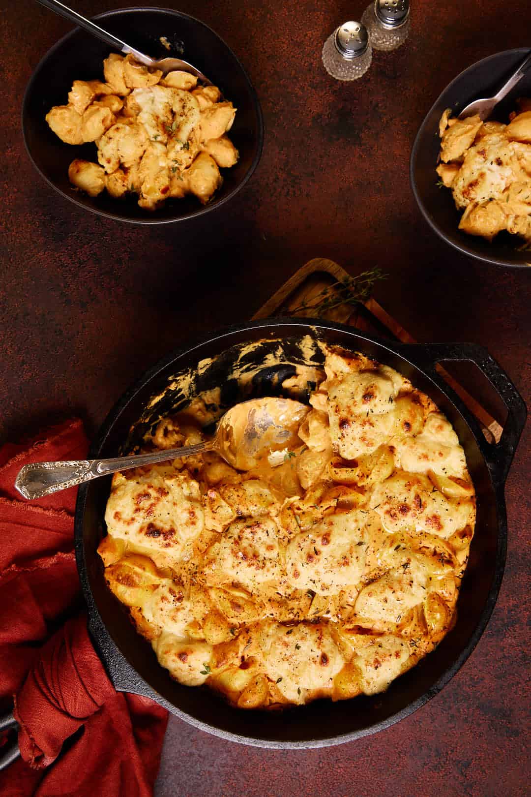 a skillet of pumpkin mac and cheese and 2 bowls with servings of pasta in.