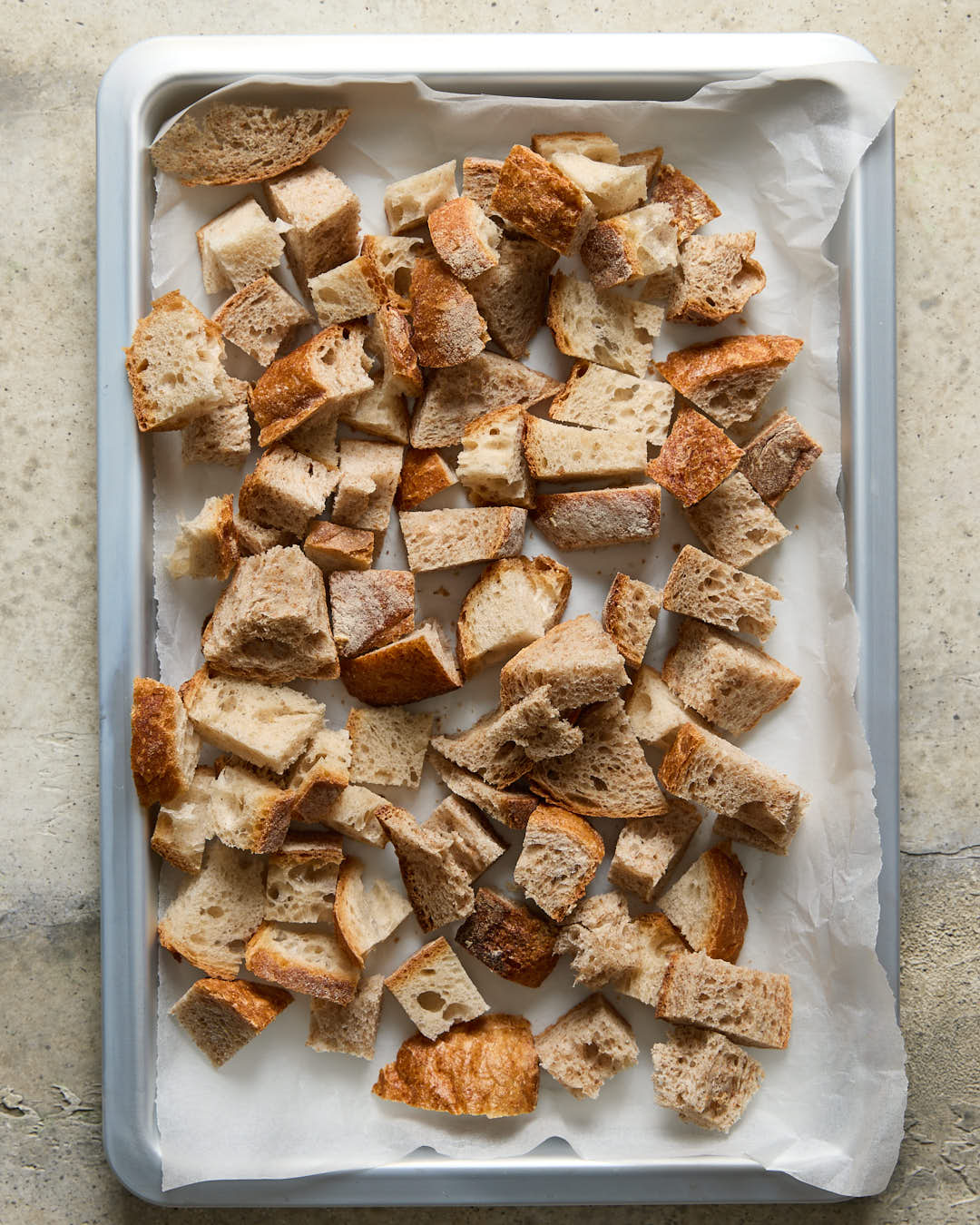 Stale bread chunks on a silver baking sheet for Lemon parsley garlic breadcrumbs