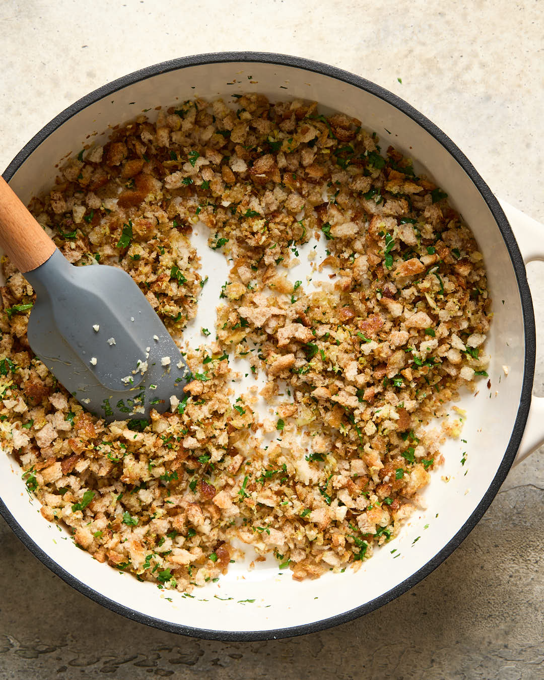 Lemon parsley garlic breadcrumbs being stirred in a cream cast iron pan 