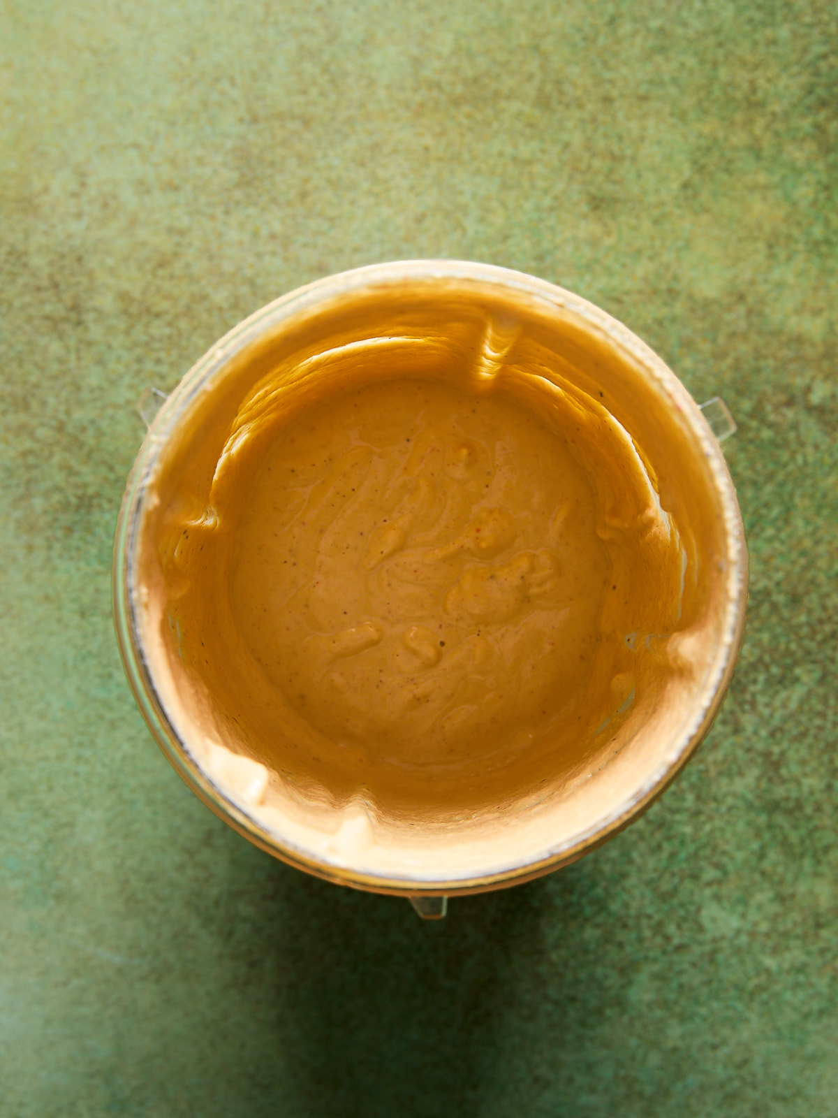 Smooth and creamy nacho-style vegan queso inside a blender cup after blending