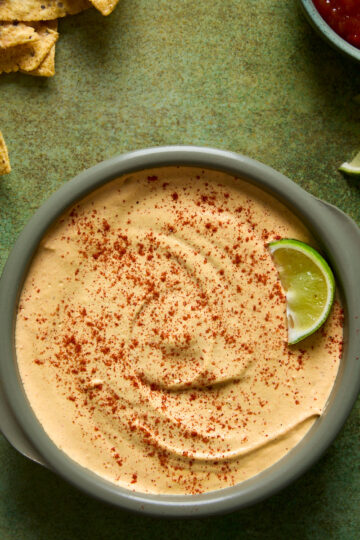 Nacho Queso Dip on a green backdrop with accompaniments