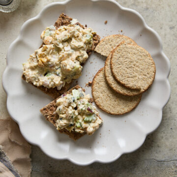 Vegan chickpea tuna salad served on crispbread with oat crackers on a scalloped plate