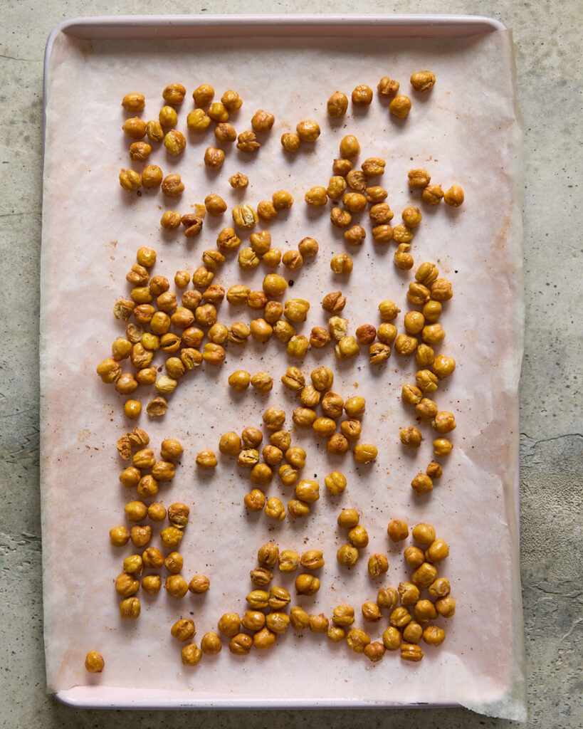 Golden roasted chickpeas on a baking tray, evenly crisped and slightly puffed.