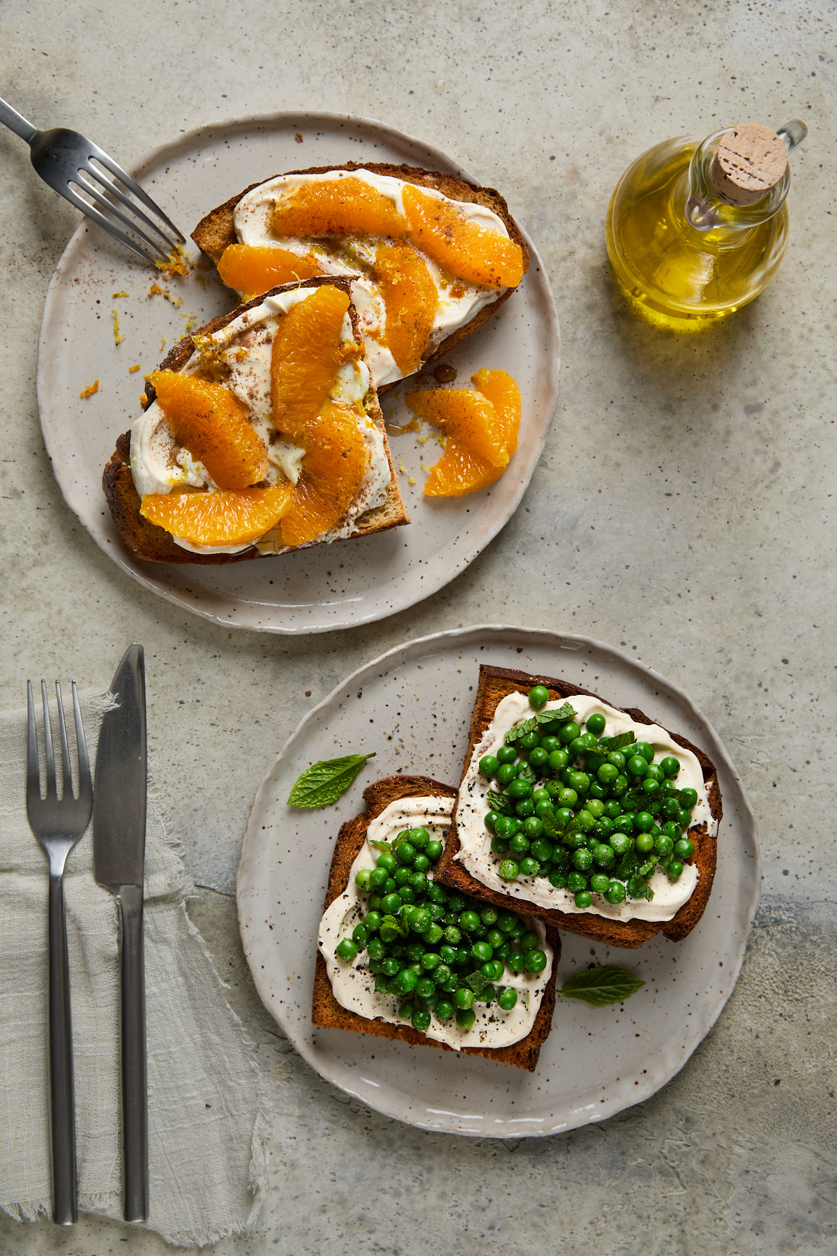 Two plates of toast—one with sweet ricotta and orange, the other with savoury ricotta and fresh green peas, mint, and cracked pepper.