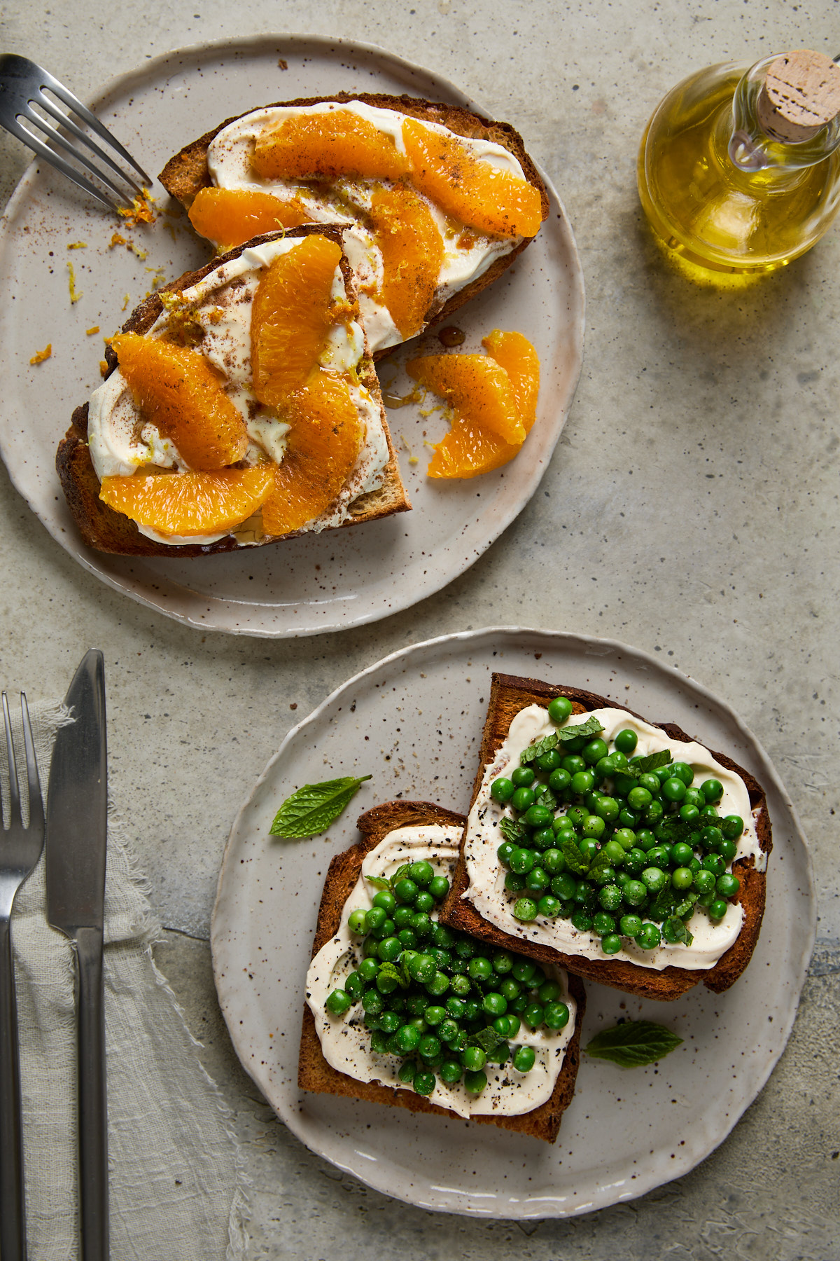 Two plates of toast-one with sweet ricotta and orange, the other with savoury ricotta and fresh green peas, mint, and cracked pepper.