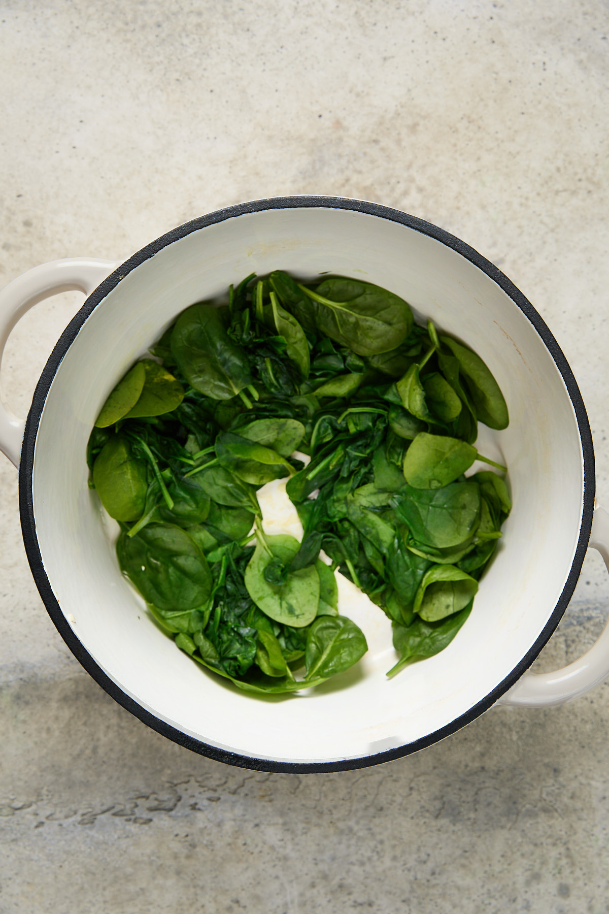 Fresh baby spinach wilting in a white pot, lightly steamed and vibrant green.