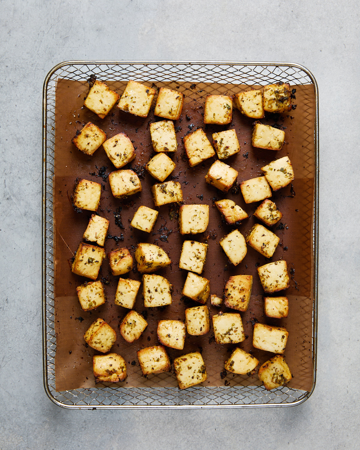 Crispy golden tofu cubes just out of the oven or air fryer, lightly charred and packed with Greek herb flavor.